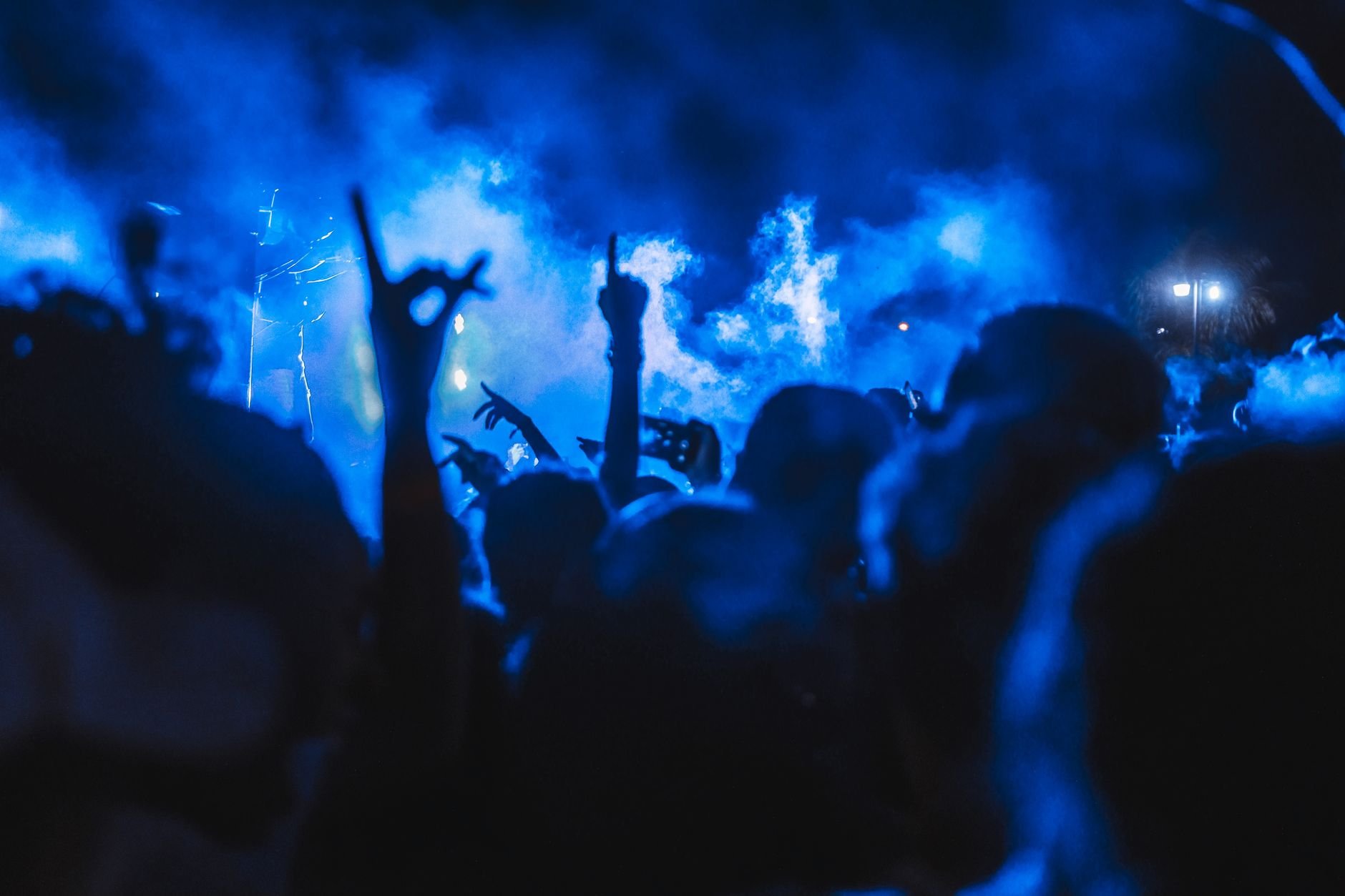 Vibrant crowd enjoying a live concert at night with stunning smoke effects creating a dynamic atmosphere.